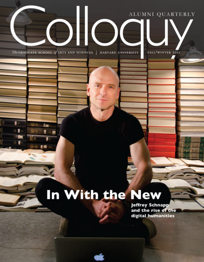 Jeffrey Schnapp sitting on the floor in front of stacks of books and behind a laptop.
