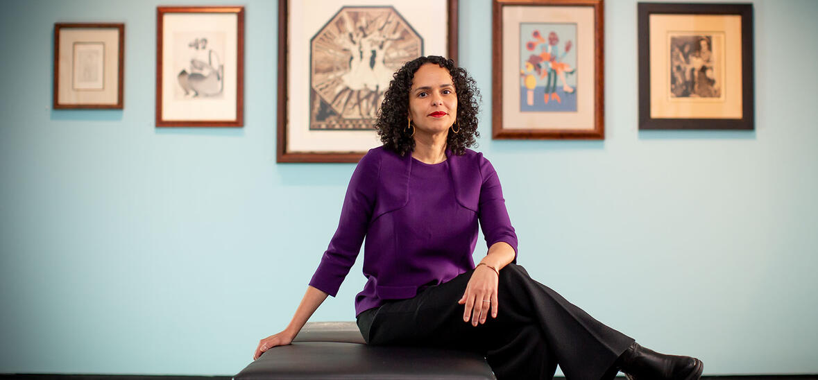 Cecile Fromont sitting on chair in Locke Gallery in front of teal wall with pictures hanging 