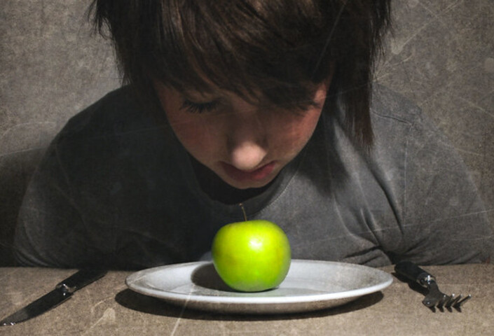 Child looking down at apple on plate