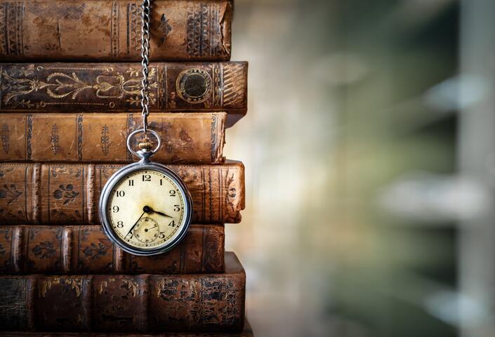 stack of old books, along with old-fashioned pocket watch hanging from them