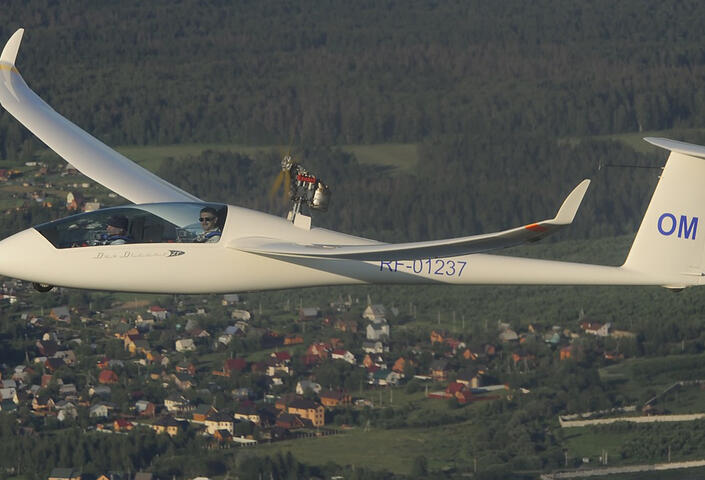 Glider in flight over small town