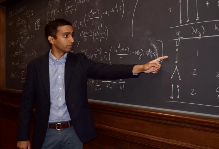 PhD student Vaibhav Mohanty lecturing at a blackboard on theoretical chemistry