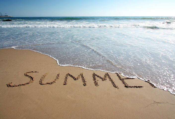 ocean tide washing away the word "Summer" written into the beach sand