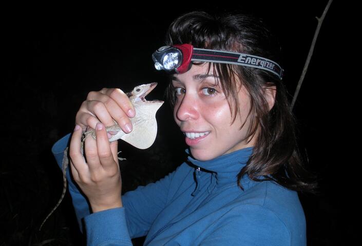 Muñoz holds a reptile species in hand towards face