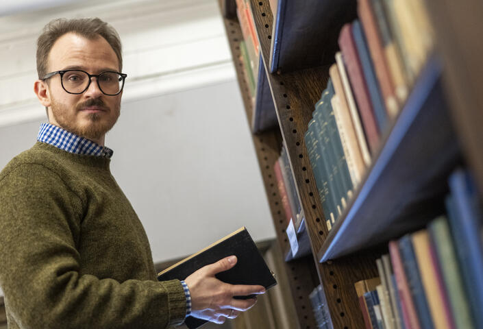 Yevhenii Monastyrskyi looking towards the camera as he reads a book