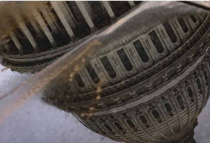 Photo of the US Capitol dome reflected upside down in a puddle of water