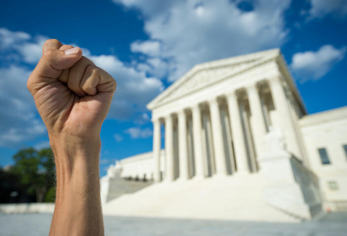 Hand clenched in fist symbol as sign of protest in front of US Supreme Court building in Washington DC.
