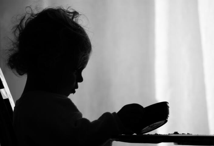 A little girl is sadly looking into her empty bowl