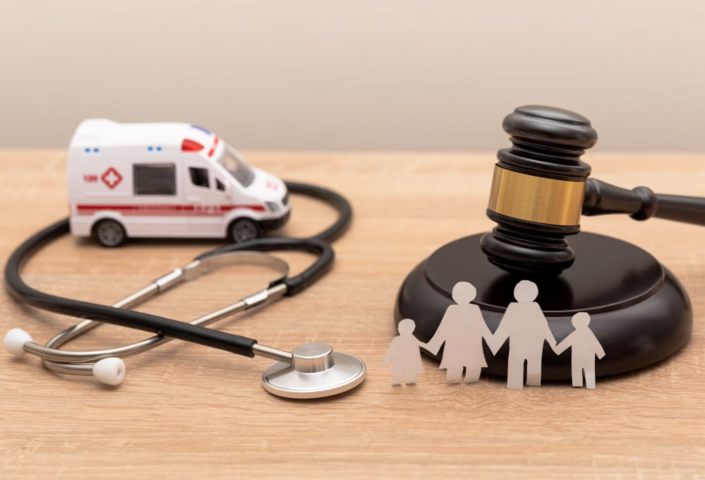 Stock photo of miniature ambulance, stethoscope, and gavel on a wood tabletop