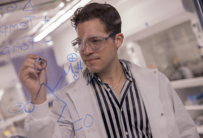 Jose in lab writing on transparent wall