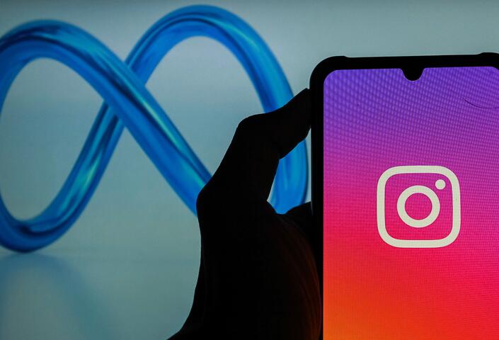 meta logo behind instagram logo on an iphone