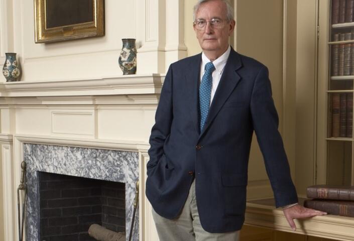 Dr. Keith Thompson standing to the right of a marble fireplace