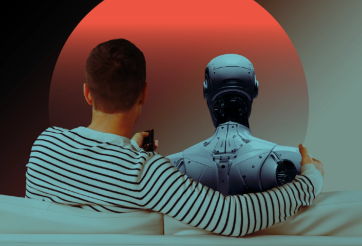 Seen from behind, a man seated on a loveseat with his arm affectionately wrapped around a robot friend. 