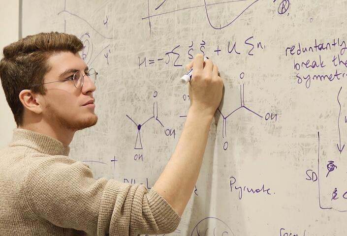Ozturk writing formulas on a white board