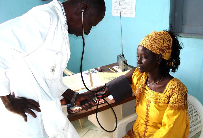 Senegalese medical professional checking a patient's blood pressure.