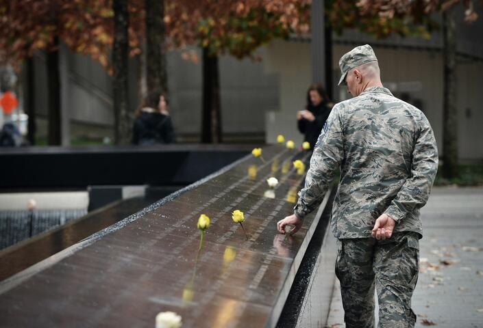 Man in military uniform looks and holds onto 9/11 memorial 