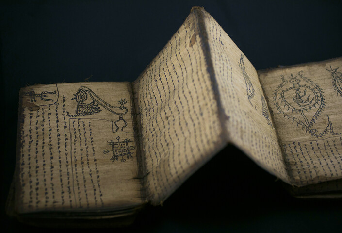 An open book with hand-drawn symbols and illustrations. The pages are folded like an accordion.