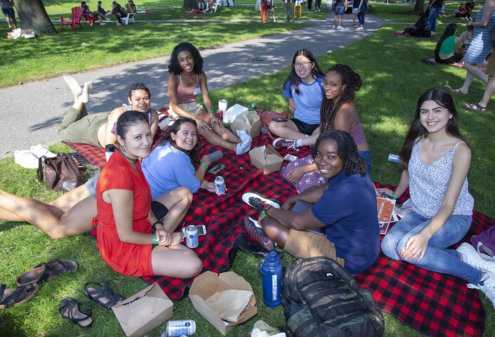 Students sitting on grass on top of blanket at GSAS Lunch on the Lawn, August 2022