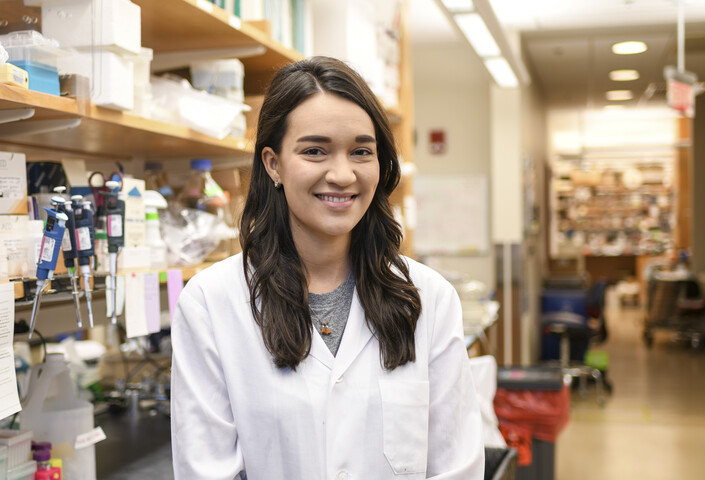 Krissy Lyon, wearing a labcoat, with scientific equipment in the background