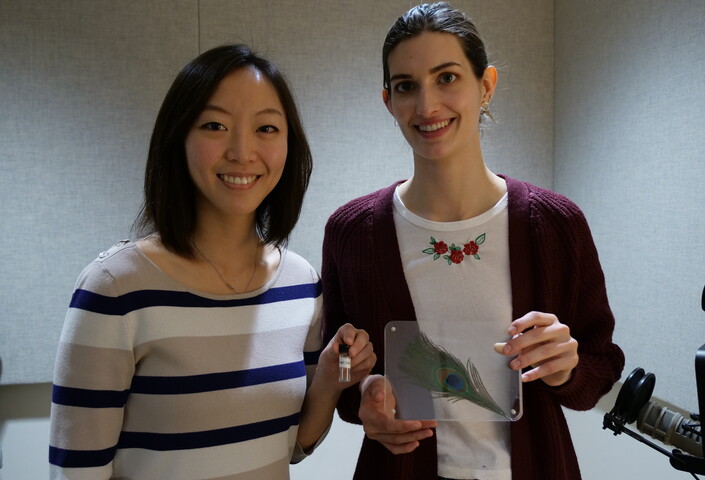 Victoria Hwang (L) holds a vial of lab-made structural color, Annie Stephenson (R) holds a peacock feather.