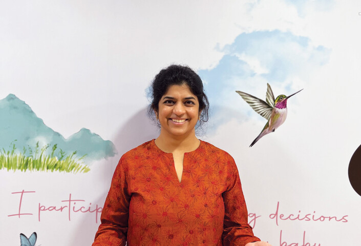 Nilekani poses in front of artwork in Aastrika Midwifery Centre