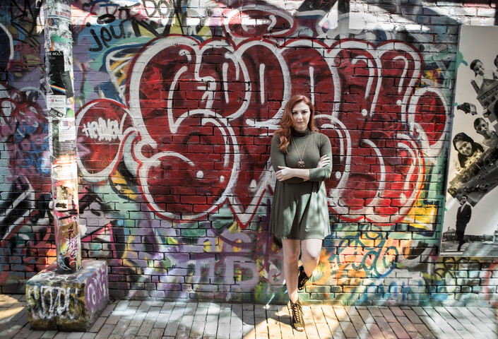 Samantha Hawkins stands against a wall filled with graffiti