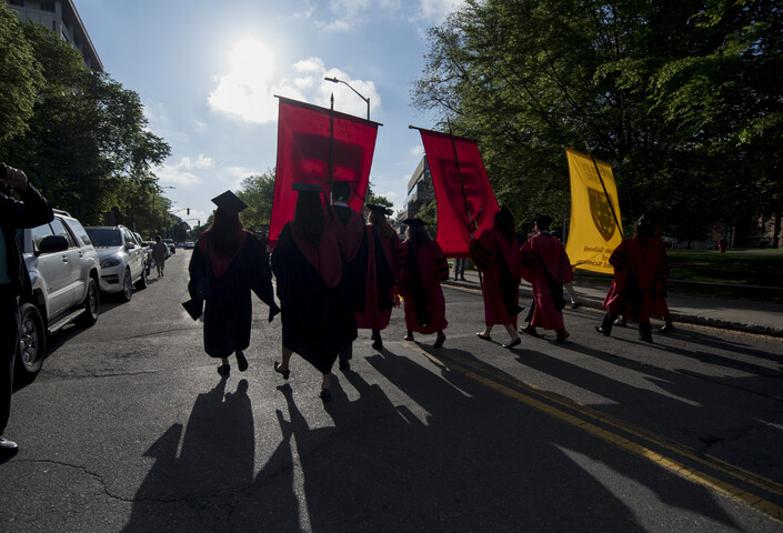 Graduates are silhouetted against a sunny background