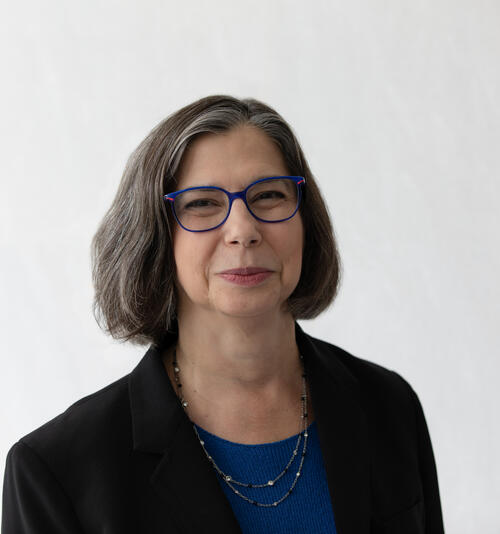 headshot of woman, with black shirt and short grayish hair and is wearing glasses