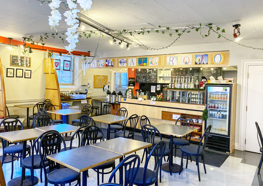 Cafe with tables, a counter, and flowers hanging from the ceiling