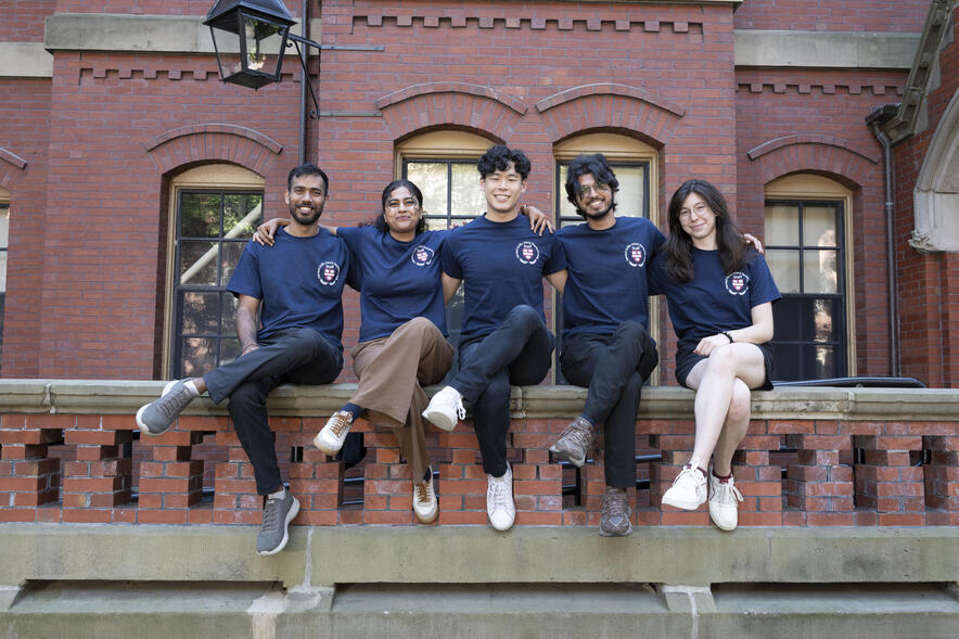 Child Hall resident advisors sit on railing of Harvard building