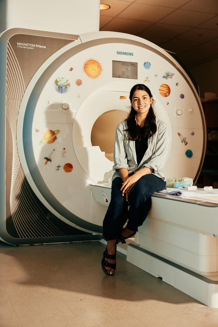 Malik-Moraleda poses with MRI machine in lab. 