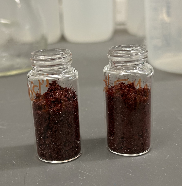 Two vials containing Campbell’s Silver 2+ photocatalyst: a vibrant, microcrystalline red powder that can be isolated on gram-scale in an analytically pure fashion. 