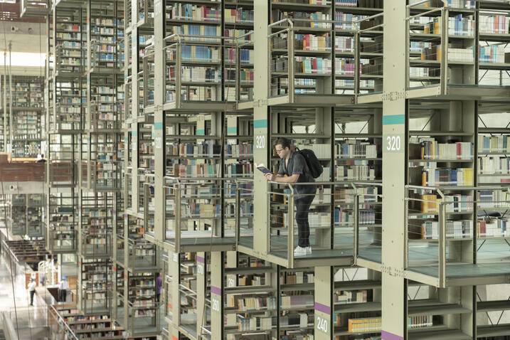 Vasconcelos Jose in Library standing on balcony looking over books.