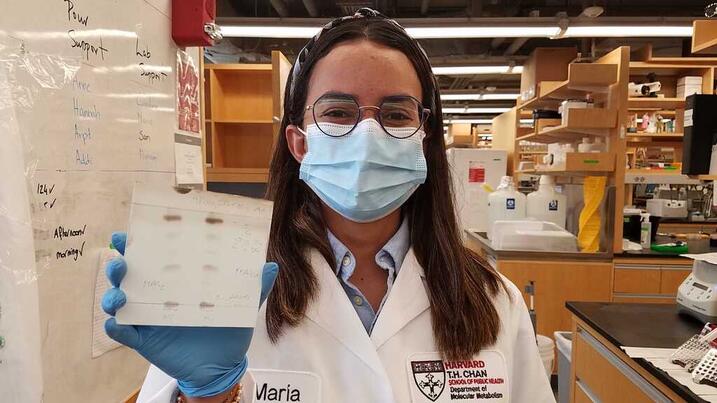 Maria holding lab samples with labcoat and mask on