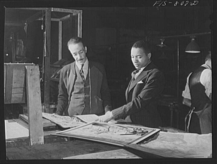 Two African American men examine a newspaper layout