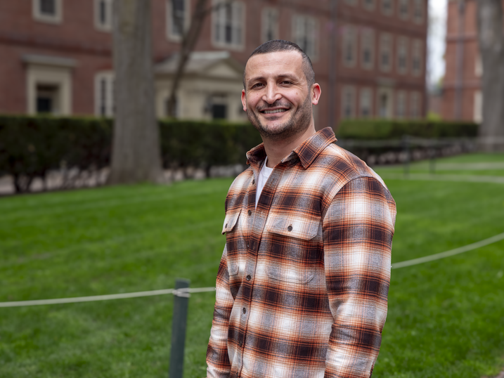 Yazan Alwadi in plaid shirt standing in Harvard Yard