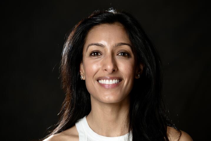 headshot of Mainieri; dark skinned, brown hair with brown eyes and big smile