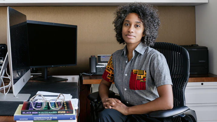 Ellora Derenencourt seated at her desk in front of two computer screens