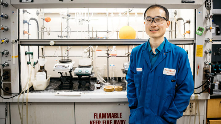 Song Lin in blue lab coat in front of his bench
