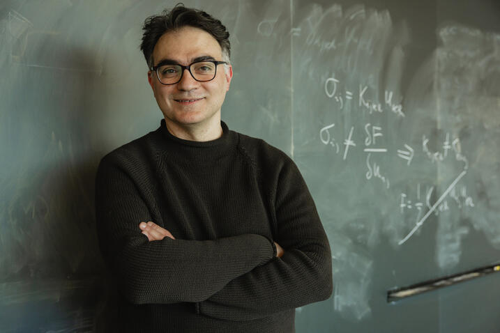 Vincenzo Vitelli standing in front of a blackboard with equations written on it in chalk