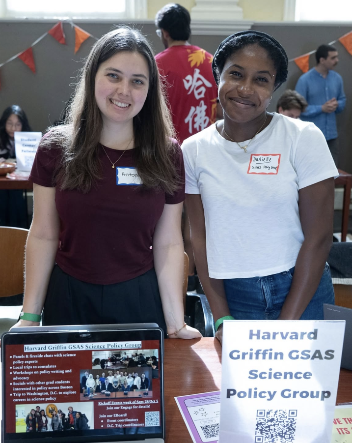 Antonia and Danielle pose in front of a Science Policy group name signage