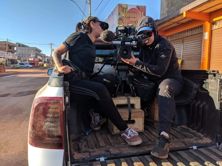 Joana Pimenta and camera assistant, Nathalya Brum, use a truck as a camera car to film motorcycle delivery workers.