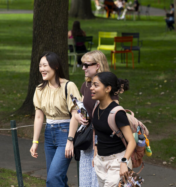 Three students smiling, walking through Harvard Yard