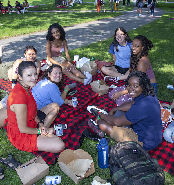 Students sitting on grass on top of blanket at GSAS Lunch on the Lawn, August 2022