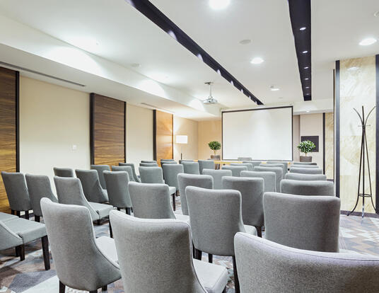 Conference room with gray chairs and screen in the back