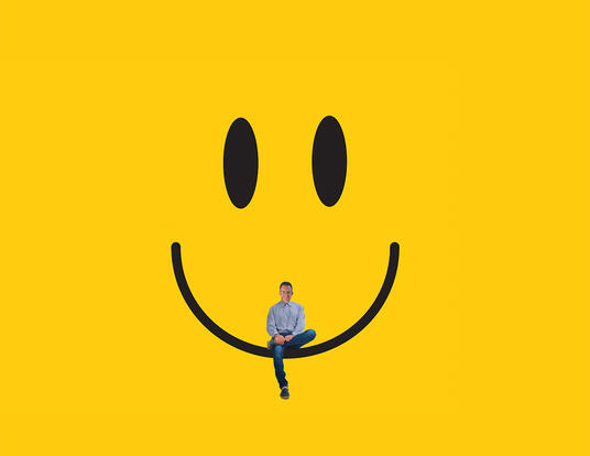 Ben Shahar sitting on a smiling face over a yellow background