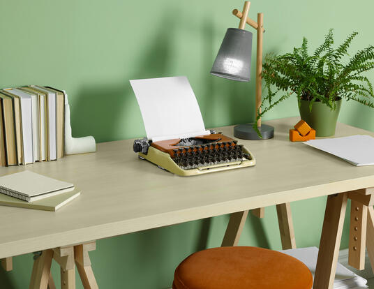 type writer on desk with lamp books notebook and plants