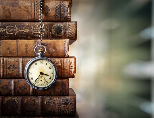 stack of old books, along with old-fashioned pocket watch hanging from them
