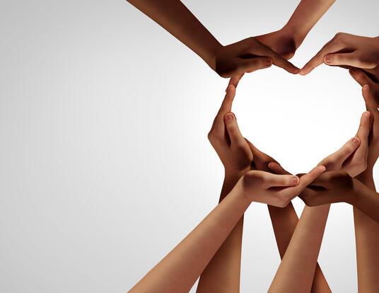 Many different hands coming together to form a heart