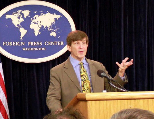 Allan Lichtman standing at podium with American flag in the background